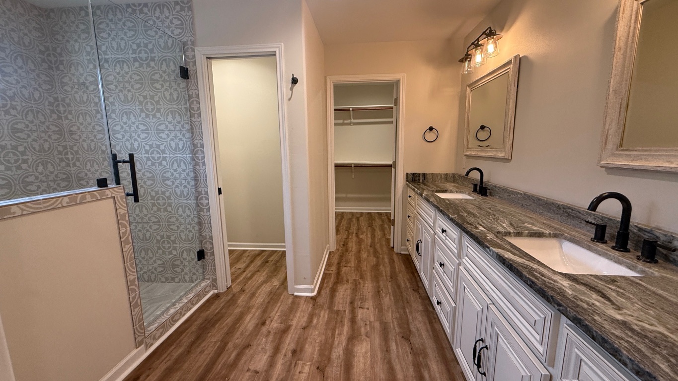 12987 Farm To Market Road 2769 Austin, TX 78726 - Photo 8 of 24 Full bathroom with double vanity, dark wood-style floors, a walk in closet, and a stall shower