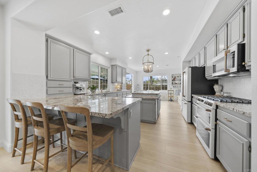 31401 Chemin Chevalier Temecula, CA 92591 - Photo 38 of 74 a kitchen with stainless steel appliances granite countertop a stove top oven a sink dishwasher a dining table and chairs with wooden floor