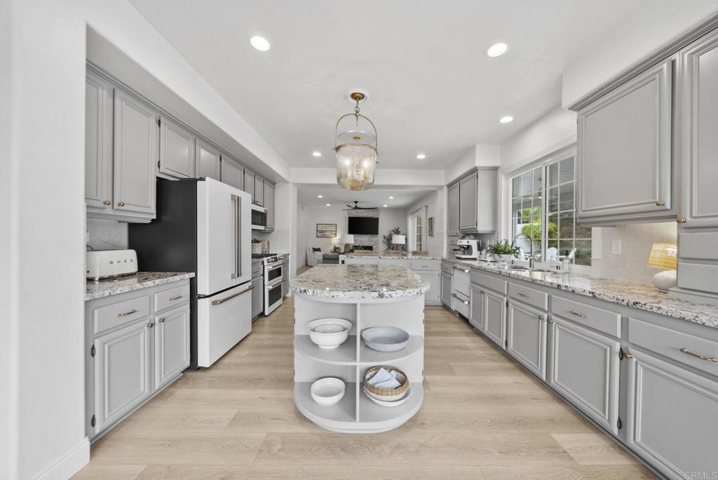 31401 Chemin Chevalier Temecula, CA 92591 - Photo 39 of 74 a kitchen with stainless steel appliances kitchen island granite countertop a refrigerator a stove top oven a sink dishwasher and white cabinets with wooden floor