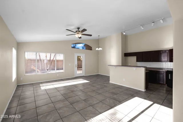 a view of an empty room with a kitchen and a window