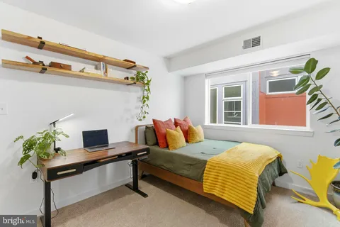 a bedroom with a bed a dresser and a potted plant