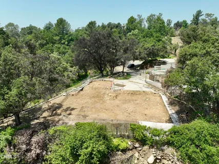 an aerial view of a house with yard and trees in the background