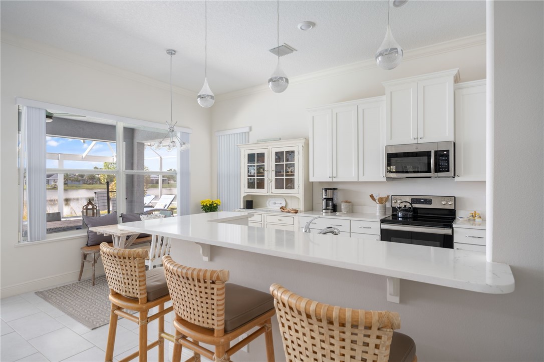 933 Yearling Trail Sebastian, FL 32958 - Photo 20 of 36 a kitchen with stainless steel appliances a stove a sink a microwave a dining table and chairs