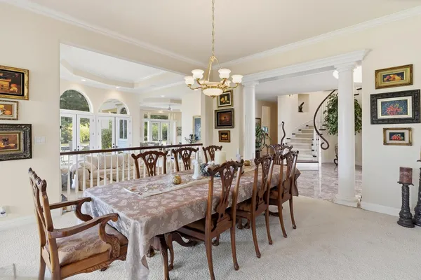 a living room with stainless steel appliances a dining table wooden floor and a kitchen view