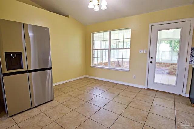 a view of an empty room with window and refrigerator