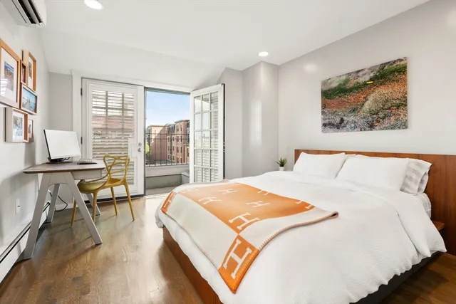 a bedroom with a large bed a large window and wooden floor