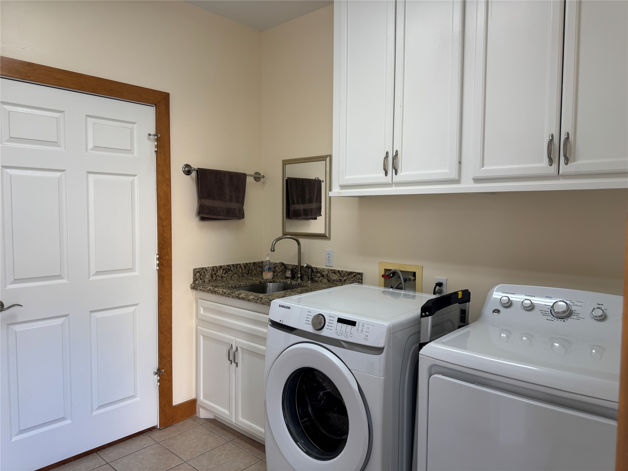 55 Lake Road Huntsville, TX 77320 - Photo 26 of 50 This laundry room features modern appliances, a spacious countertop with a sink, ample storage in white cabinets, and convenient access through a side door. Washer and dryer can stay if you want them!