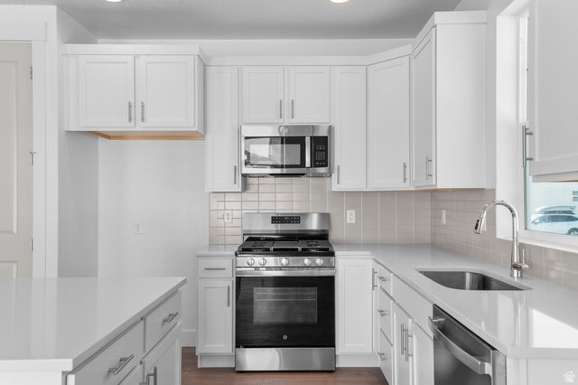 5644 Ibis Road Tooele, UT 84074 - Photo 16 of 19 Modern kitchen featuring white shaker cabinetry, stainless steel appliances, a subway tile backsplash, and light-toned countertops