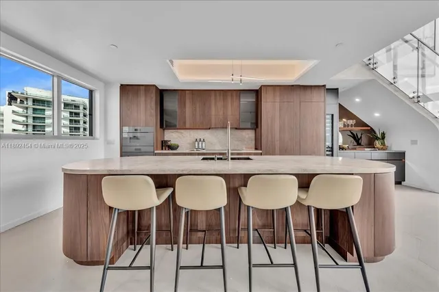 a kitchen with stainless steel appliances kitchen island granite countertop a sink and a refrigerator