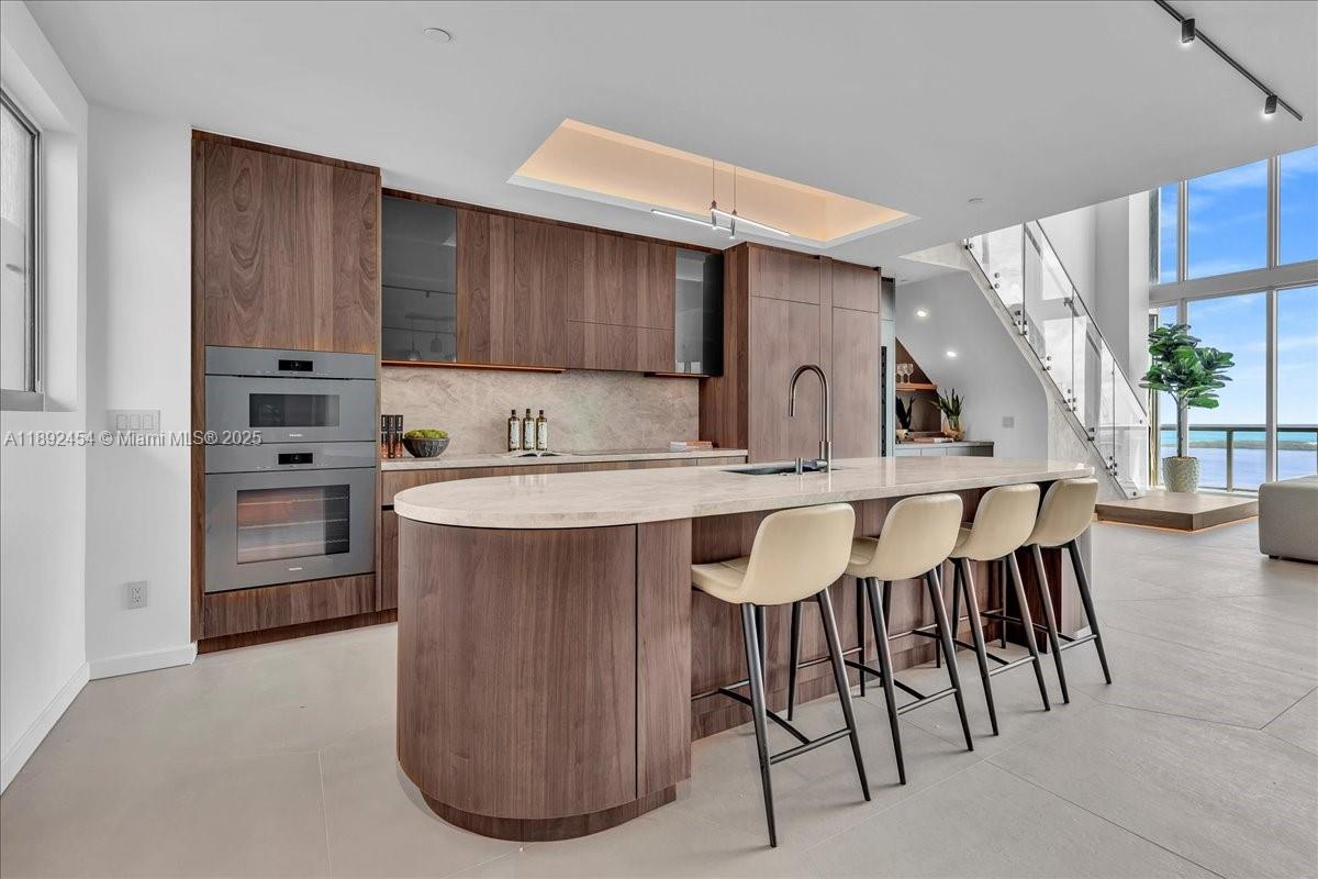 888 Biscayne Boulevard, Unit PH5704 Miami, FL 33132 - Photo 13 of 62 a kitchen with cabinets a sink and chairs