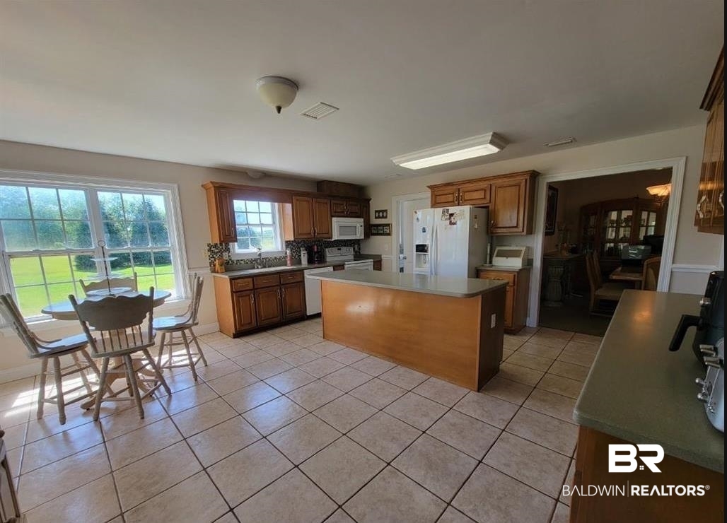 16311 Old Brady Road Bay Minette, AL 36507 - Photo 8 of 38 Spacious kitchen featuring tile flooring, wooden cabinetry, an expansive island with countertop, and double windows overlooking green space