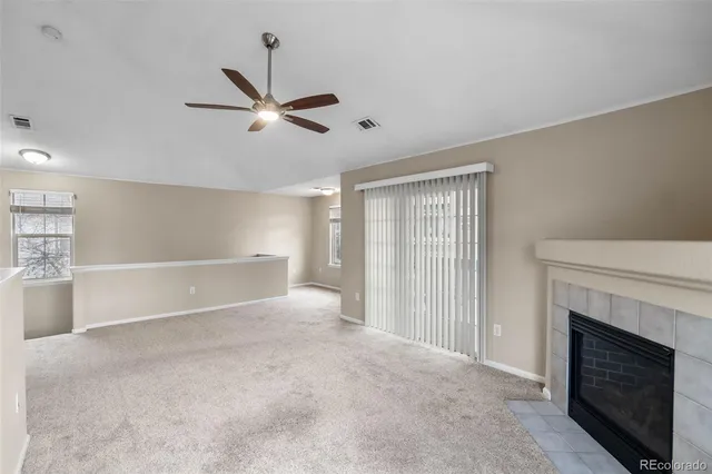 a view of an empty room with chandelier fan and fire place