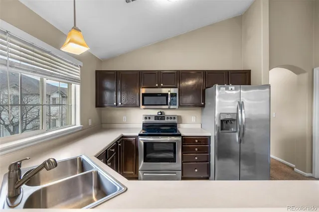 a kitchen with granite countertop a refrigerator oven a sink a stove and a window