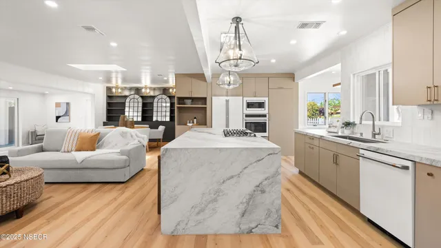 a large living room with stainless steel appliances kitchen island granite countertop a couch and a view of living room