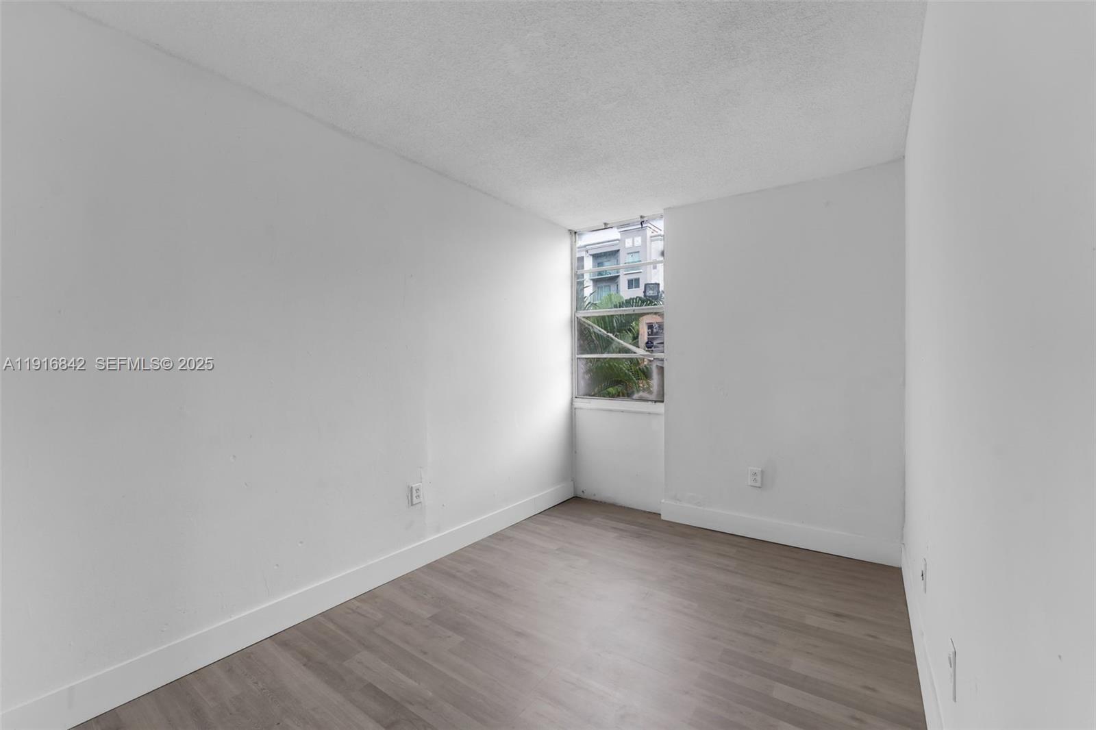 6011 Southwest 69th Street, Unit 72 South Miami, FL 33143 - Photo 9 of 22 a view of an empty room with wooden floor and a window