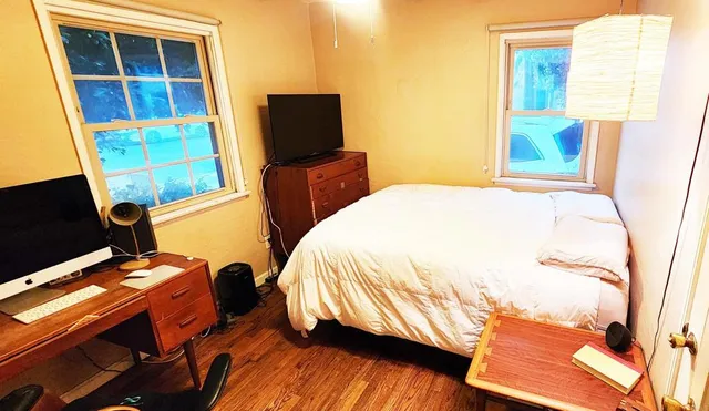 a bedroom with a bed and a flat tv screen on the dresser