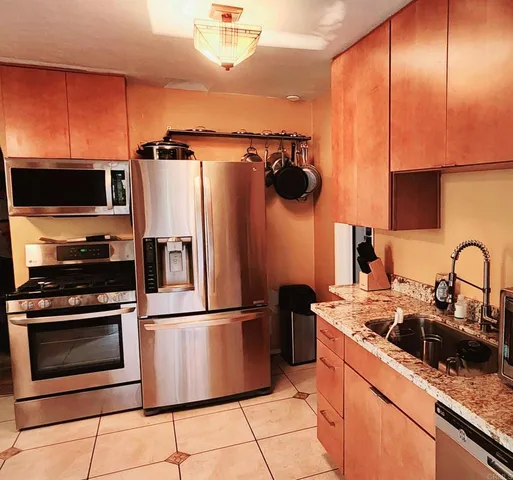 a kitchen with stainless steel appliances granite countertop a sink a stove and a refrigerator
