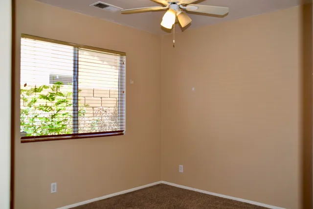 an empty room with a window and a fan