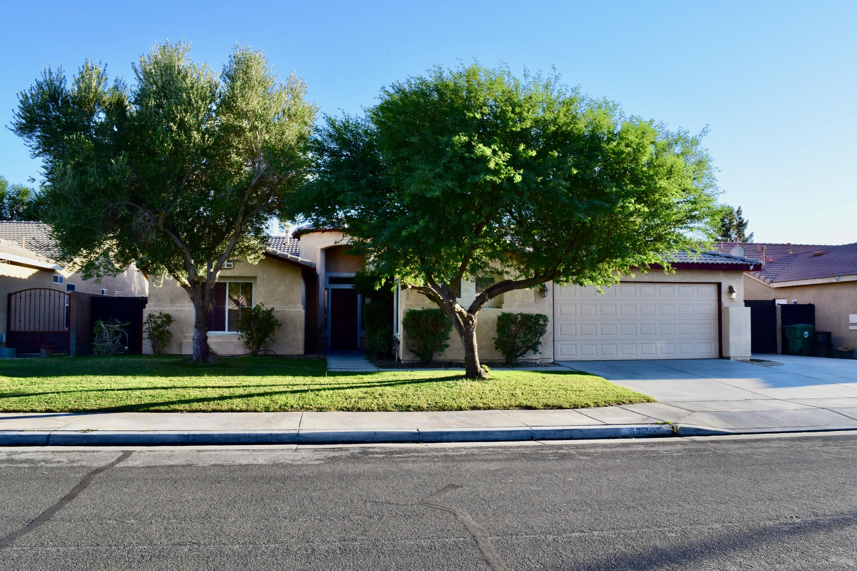 83793 Pacifica Sur Indio, CA 92203 - Photo 4 of 22 a front view of a house with a garden and trees