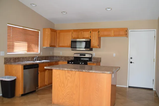 a kitchen with granite countertop a sink stove and refrigerator