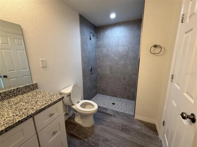 a bathroom with a granite countertop toilet a sink and a mirror