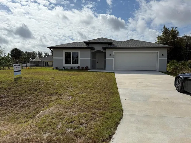 a front view of house with yard and trees in the background