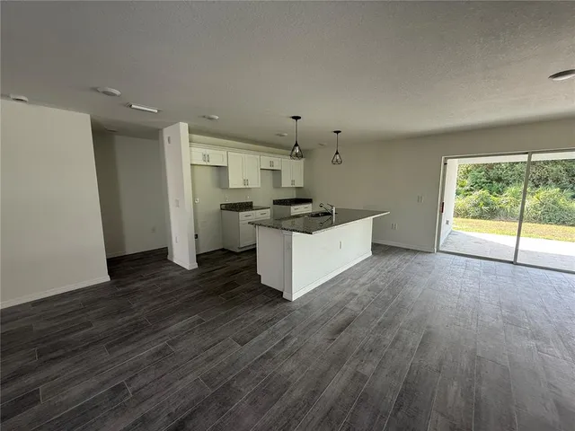a large kitchen with stainless steel appliances a large counter top a stove and a wooden floor