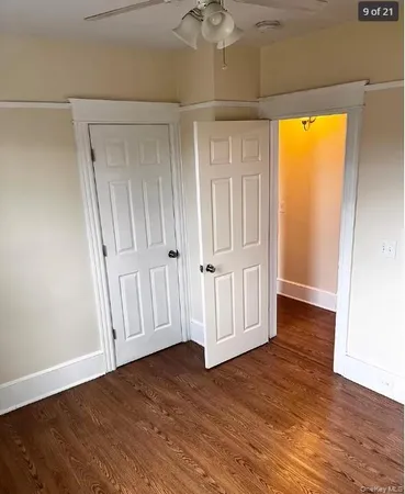a view of empty room with wooden floor and fan