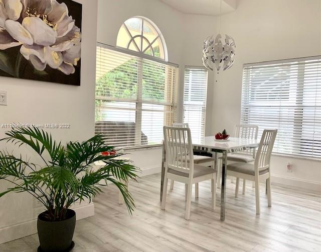 8181 Horseshoe Bay Road Boynton Beach, FL 33472 - Photo 12 of 41 a view of a dining room with furniture a chandelier and wooden floor
