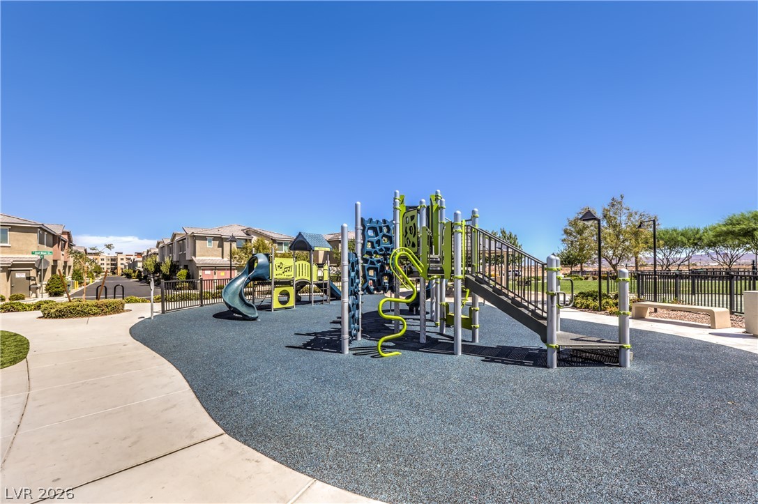 12103 Mojave Gold Road, Unit 4 Las Vegas, NV 89183 - Photo 23 of 23 An inviting community playground features safety surfacing alongside paved walking paths under clear blue skies.
