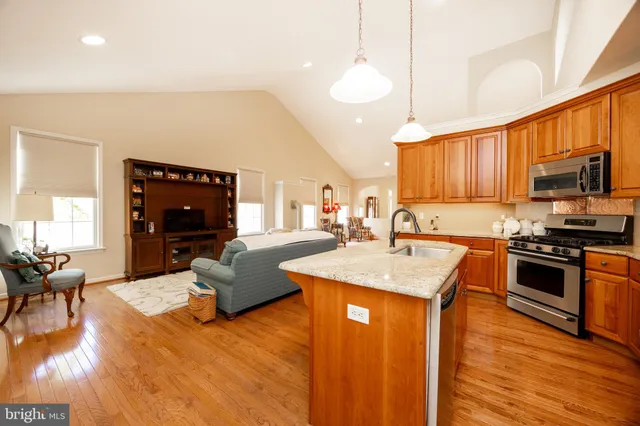 a kitchen with granite countertop a stove top oven a sink dishwasher a dining table and chairs with wooden floor