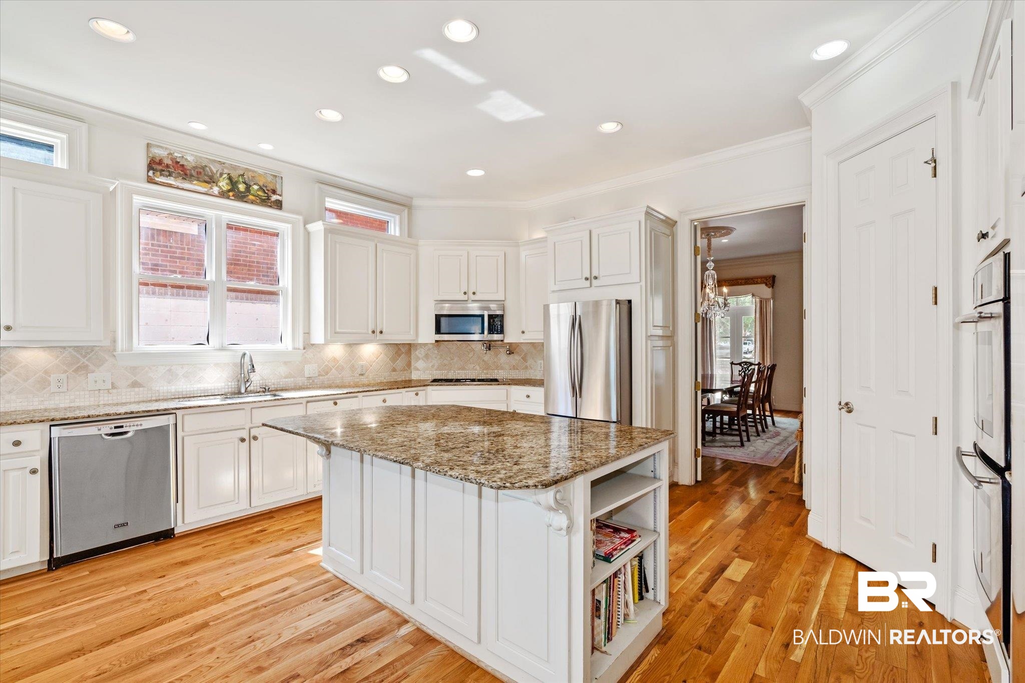 3963 Wimbledon Park Mobile, AL 36608 - Photo 9 of 51 Kitchen with appliances with stainless steel finishes, decorative backsplash, light stone counters, light wood-type flooring, and a kitchen island