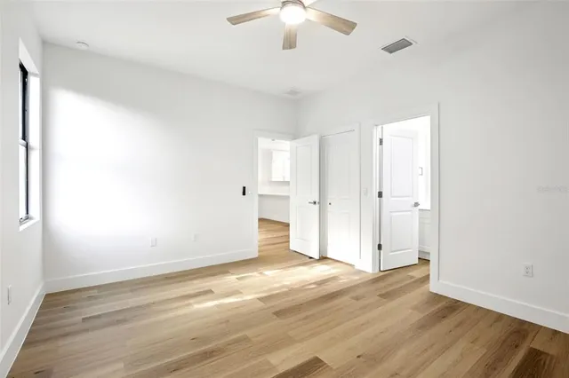 an empty room with wooden floor and a ceiling fan