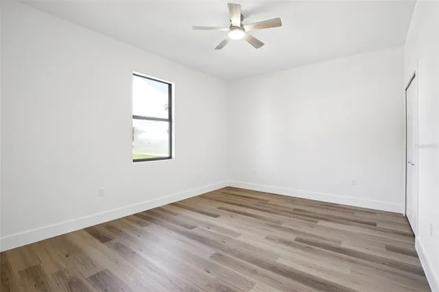 an empty room with wooden floor closet and windows