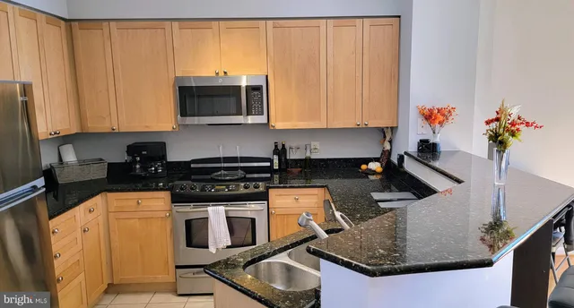 a kitchen with stainless steel appliances granite countertop a sink a stove and a microwave