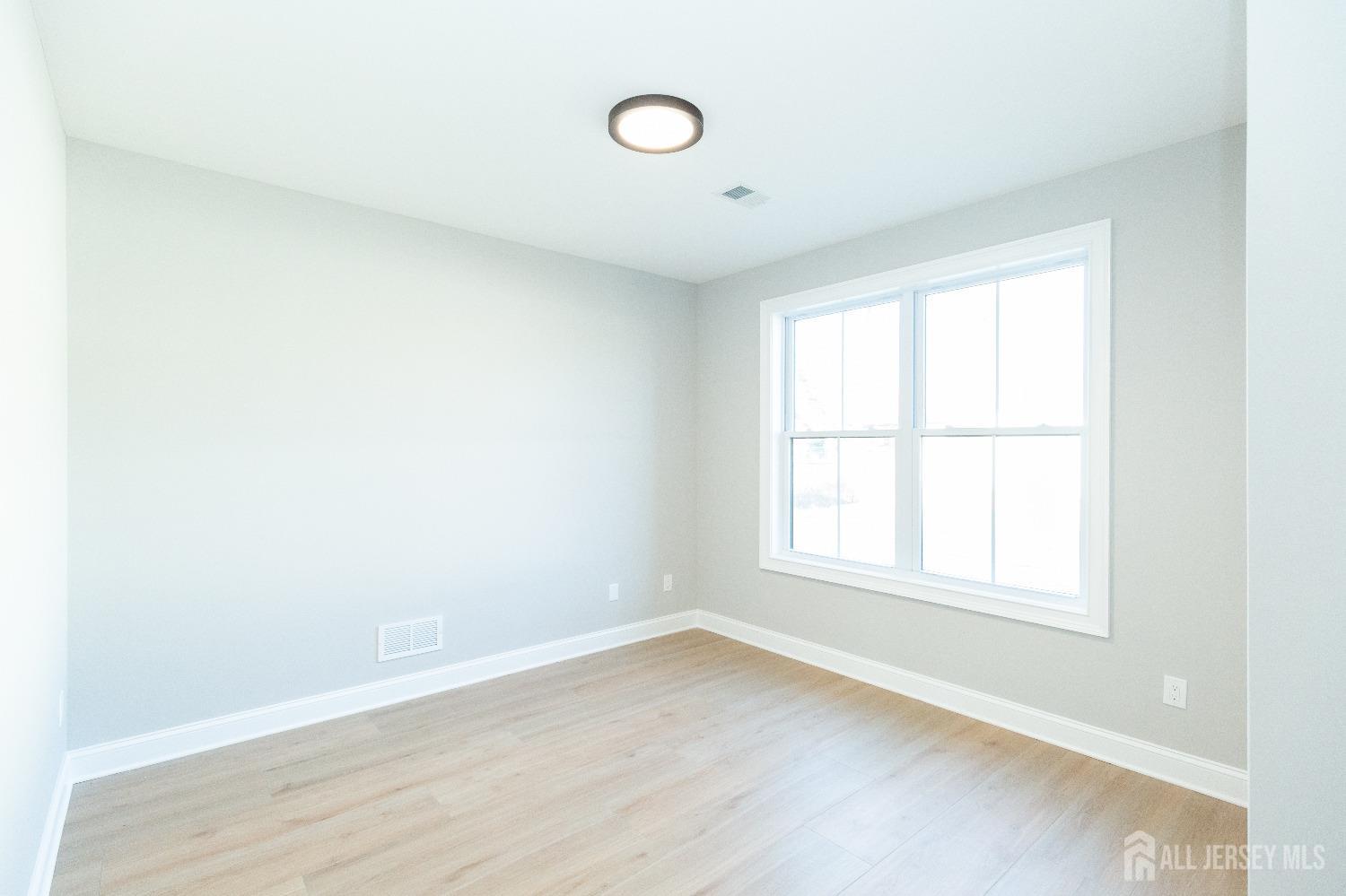 24 Parkerson Road Edison, NJ 08817 - Photo 20 of 56 an empty room with wooden floor and windows