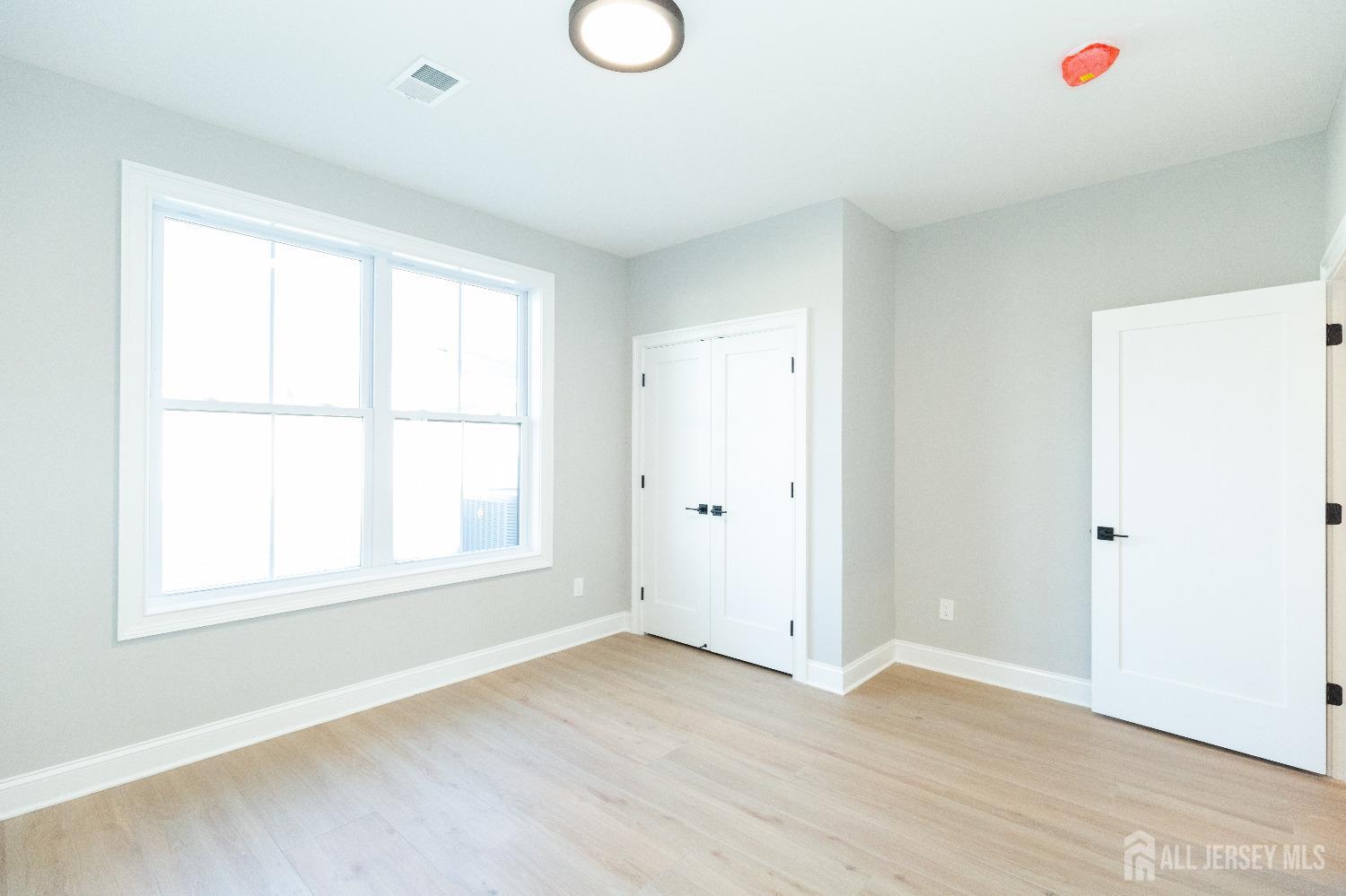 24 Parkerson Road Edison, NJ 08817 - Photo 21 of 56 an empty room with wooden floor and windows