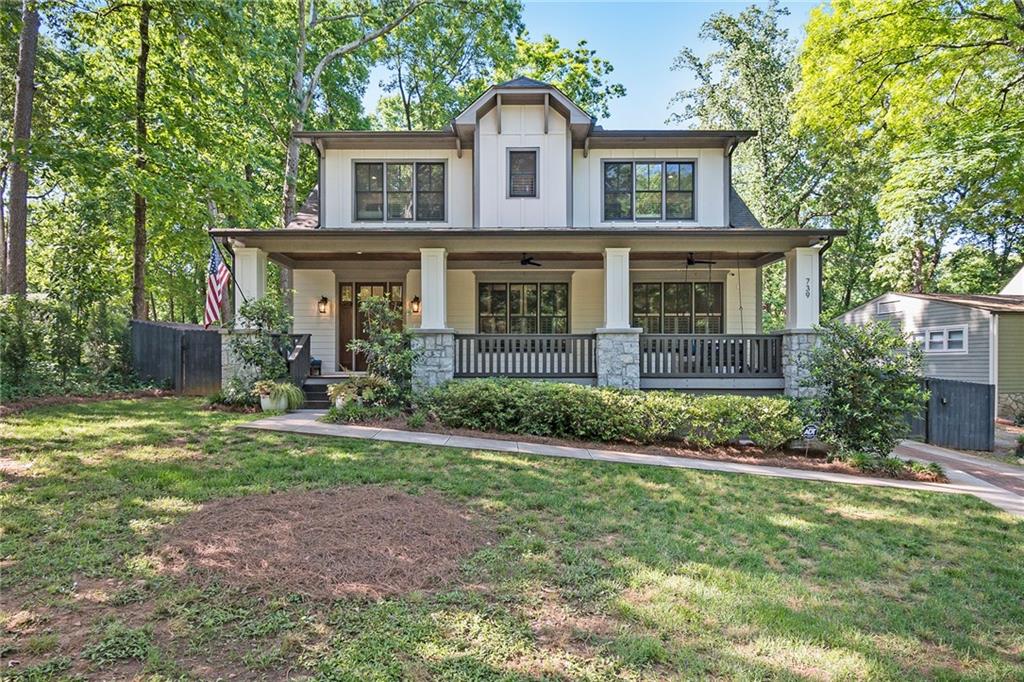 a view of a brick house with a yard and large trees