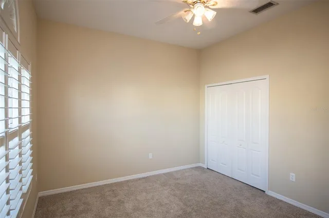 an empty room with a chandelier fan and windows