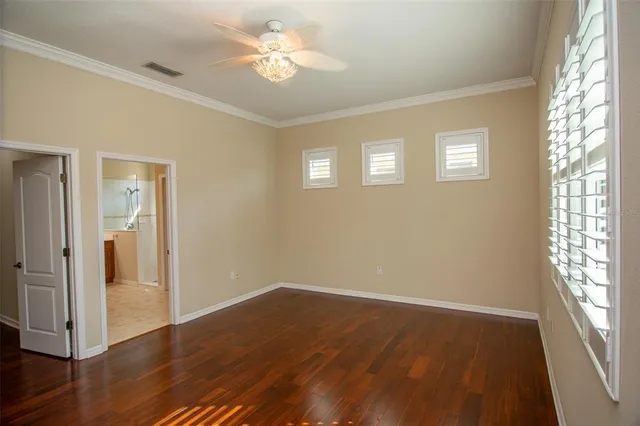 a view of empty room with wooden floor and fan