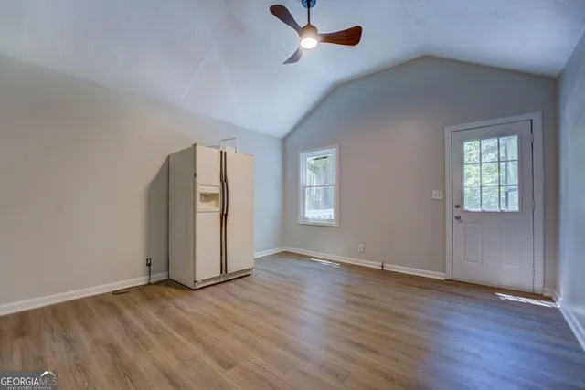 an empty room with wooden floor cabinet and windows