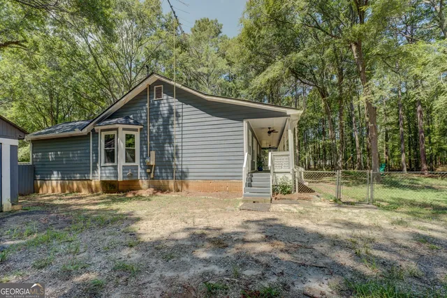 a backyard of a house with wooden fence and large trees