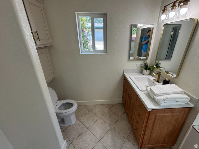 11313 South 265 East Sandy, UT 84070 - Photo 8 of 21 Bathroom featuring a single vanity with a light-colored countertop, wood-finish cabinetry, and a rectangular sink with a gold-tone faucet
