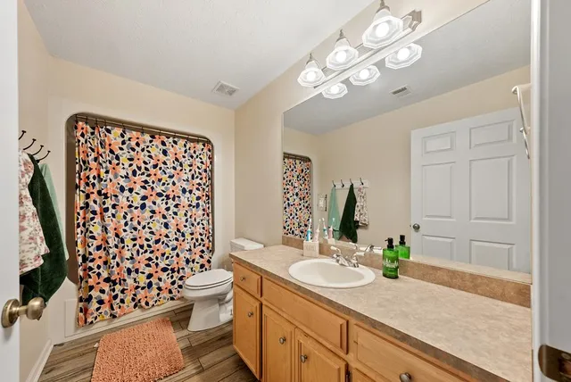 a bathroom with a granite countertop toilet sink and mirror