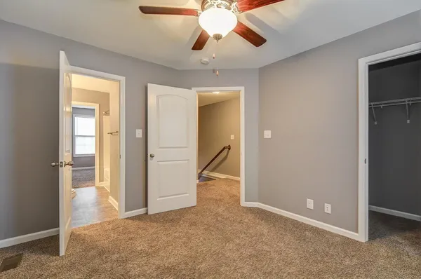 an empty room with closet and a chandelier fan