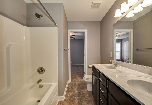 a bathroom with a granite countertop sink a toilet and shower