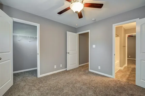 an empty room with closet and a chandelier fan