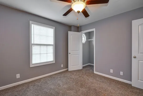 an empty room with windows and chandelier fan