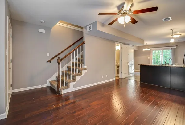a view of an empty room with wooden floor and a ceiling fan