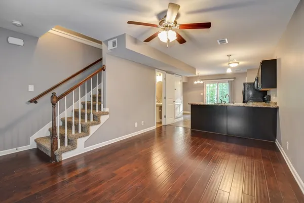 a view of an empty room with wooden floor and a kitchen
